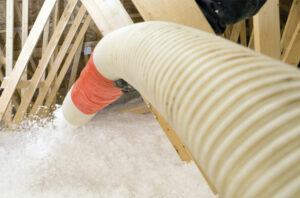 stock photo of hose blowing loose-fill fiberglass insulation into attic space