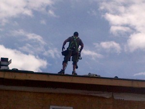roofer tied off using harness on roof