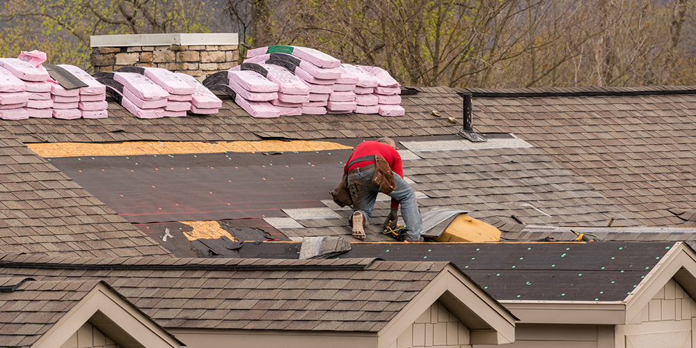 A professional roofer in Calgary, Alberta, is installing shingles on a residential roof, demonstrating proper roofing techniques and ensuring a durable and weather-resistant finish.